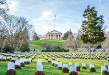 Cemetery with rows of tombstones and wreaths.