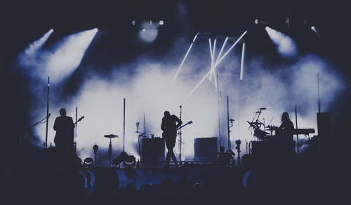 Band performing on stage with dramatic lighting effects.