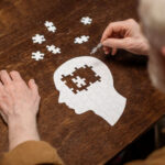 Justice PARALYZED — Shocking INCOMPETENCY Ruling Elderly person assembling a head-shaped jigsaw puzzle on a wooden table