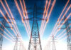 High-voltage transmission towers with glowing power lines at dusk