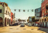 Venice Beach street with sign over road, sunny day.