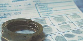 Handcuffs resting on a fingerprint card with inked fingerprints