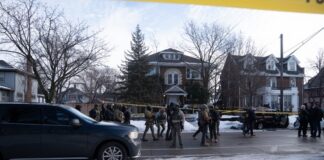 Law enforcement officers in tactical gear at a crime scene surrounded by police tape