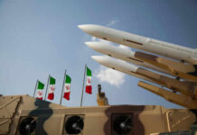Iran Admits Crisis, Plots Crackdowns Missiles on launchers beside Iranian flags.