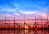 Electrical substation and power lines at sunset with vivid sky and reflections